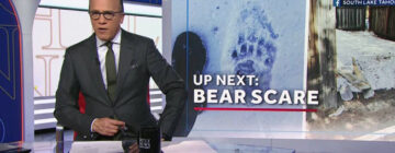 A news anchor sitting in front of an 'up next' graphic