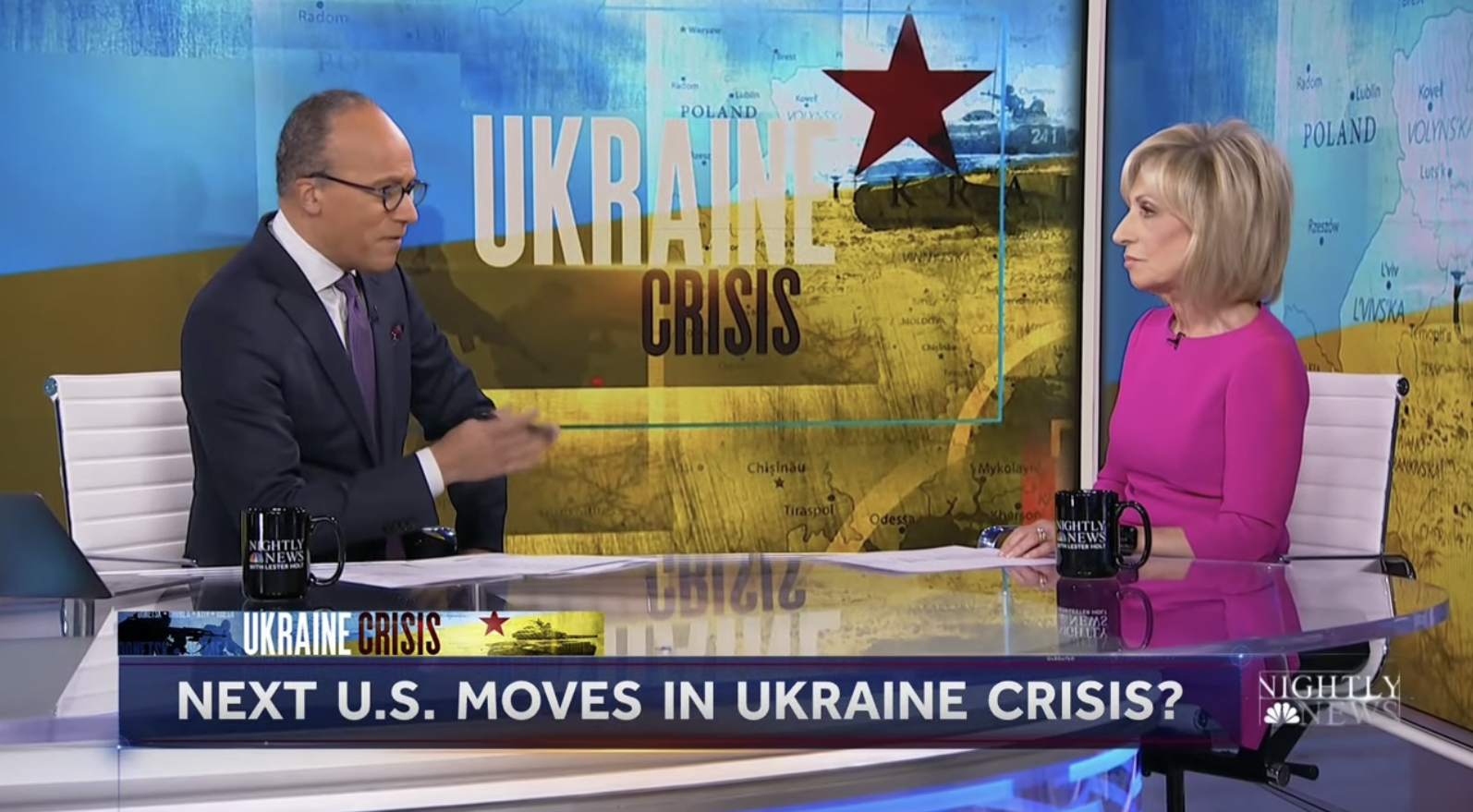 Two anchors at an anchor desk with 'Ukraine Crisis' graphics behind them